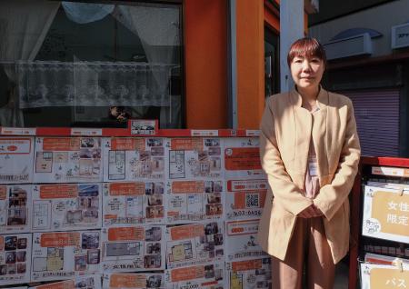 「あつまる不動産　高円寺本店」の店頭に立つ小泉厚子さん。「女性限定」の看板や物件情報が並ぶ