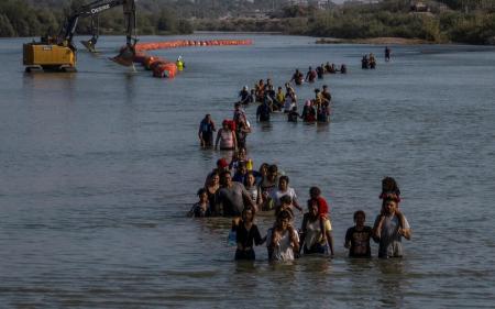 米テキサス州イーグルパスに入るため、川に設置されたブイの間を通る移民の一団＝２０２３年７月（ロイター＝共同）