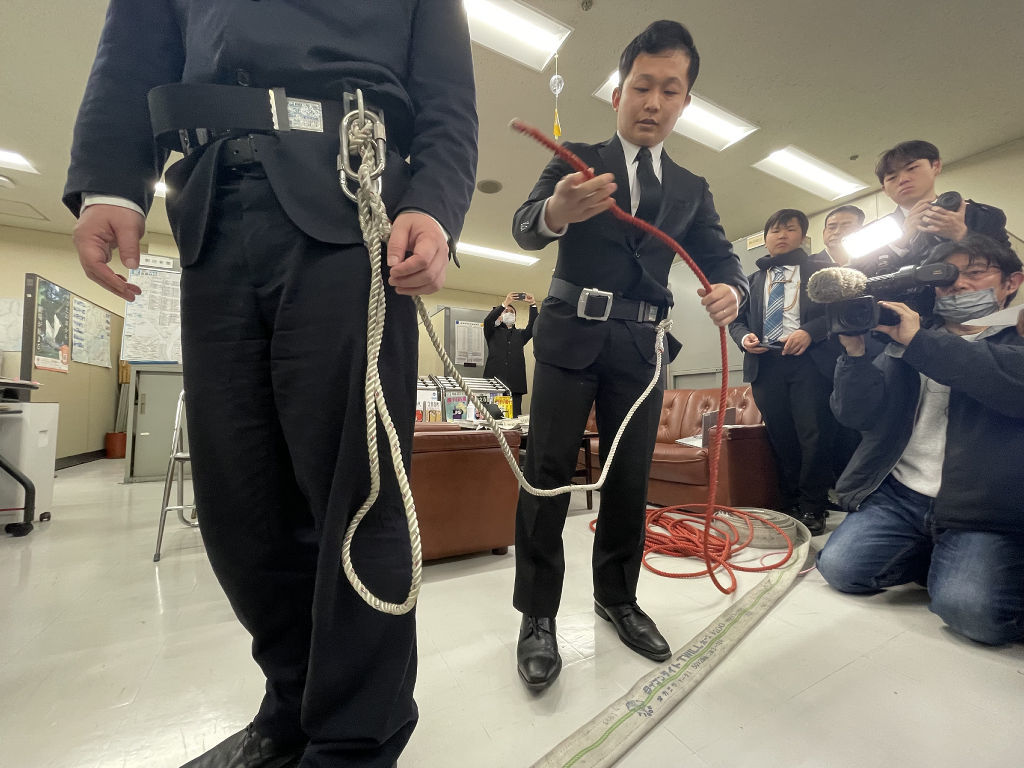 命綱を使った場合の活動を実演する元消防隊員の男性＝６日午後、静岡市役所