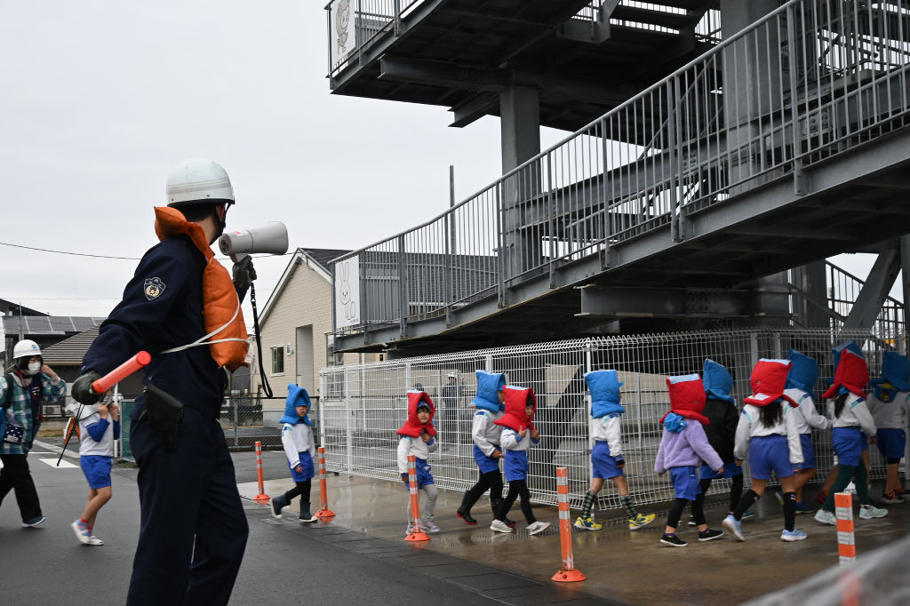 警察官の誘導で津波避難施設に避難する園児たち＝７日午前９時１０分ごろ、袋井市