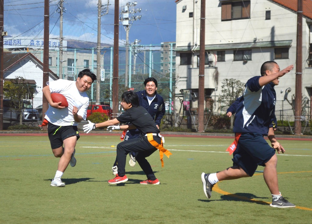 アメリカンフットボールを高校生と一緒に楽しむ参加者＝長泉町の竹原グラウンド