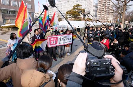 同性婚を巡る訴訟で初の高裁判断となった札幌高裁判決を受け、高裁前でメッセージを掲げる原告ら＝１４日午後