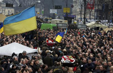 ２０１４年２月、ウクライナの首都キーウで、死亡したデモ参加者のひつぎを運ぶ人々（ロイター＝共同）
