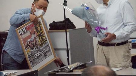 阪神・日本一の号外と花束を支援スタッフから贈られるＹさん（右）