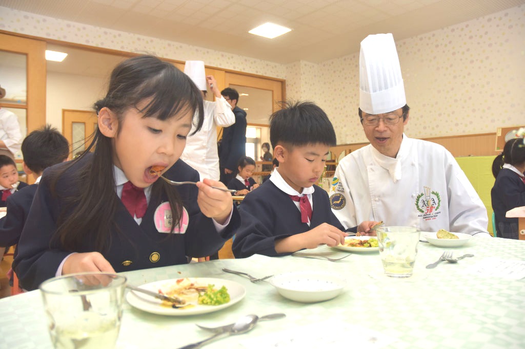 中道さん（右）が見守る中、ナイフとフォークを上手に使い、料理を味わう園児＝浜松市中央区の入野こども園