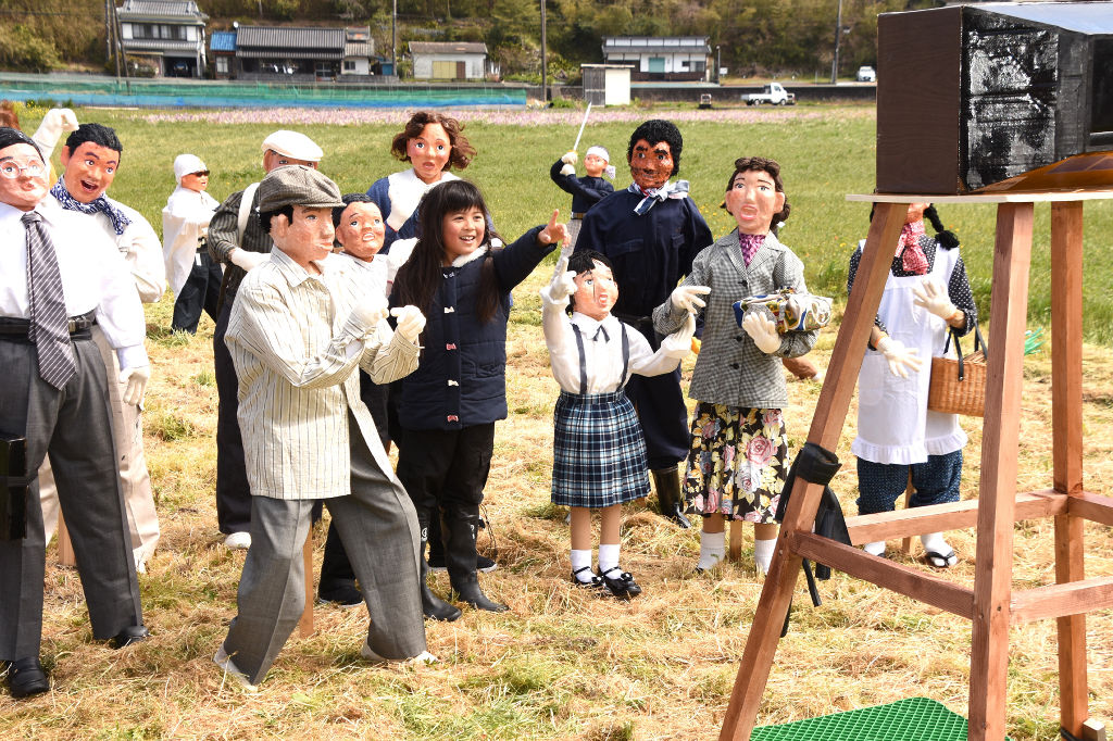 人間そっくりの「リアルかかし」と一緒に写真を撮る子ども＝松崎町那賀の「田んぼをつかった花畑」