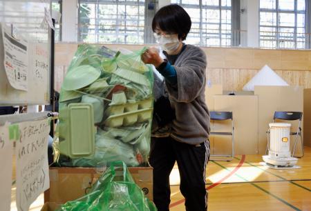 避難所となっている石川県能登町立能都中で、ごみの袋を片付ける町職員の伊勢初香さん＝２月