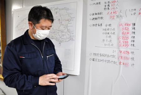 石川県珠洲市役所で、健康管理システムのスマートフォン画面を見る市職員の石尾泰宏さん＝２月