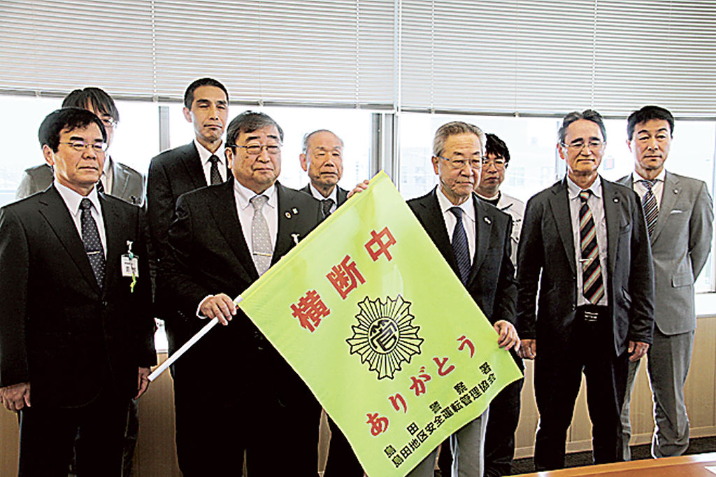 山中教育長に横断旗を手渡した岡本会長（右から４人目）＝島田市役所