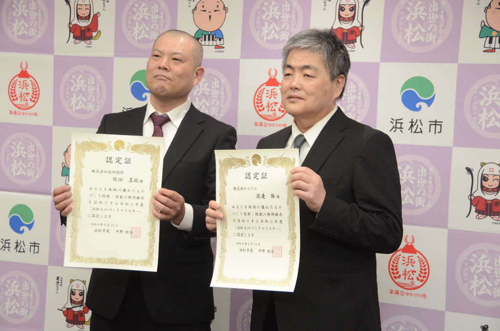 浜松ものづくりマイスターの認定証を手にする牧田技研の牧田社長（左）とエコムの渡辺さん＝浜松市役所