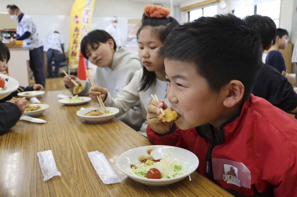 （提供写真）黒はんぺんフライを試食する児童＝焼津市大井川児童センターとまとぴあ