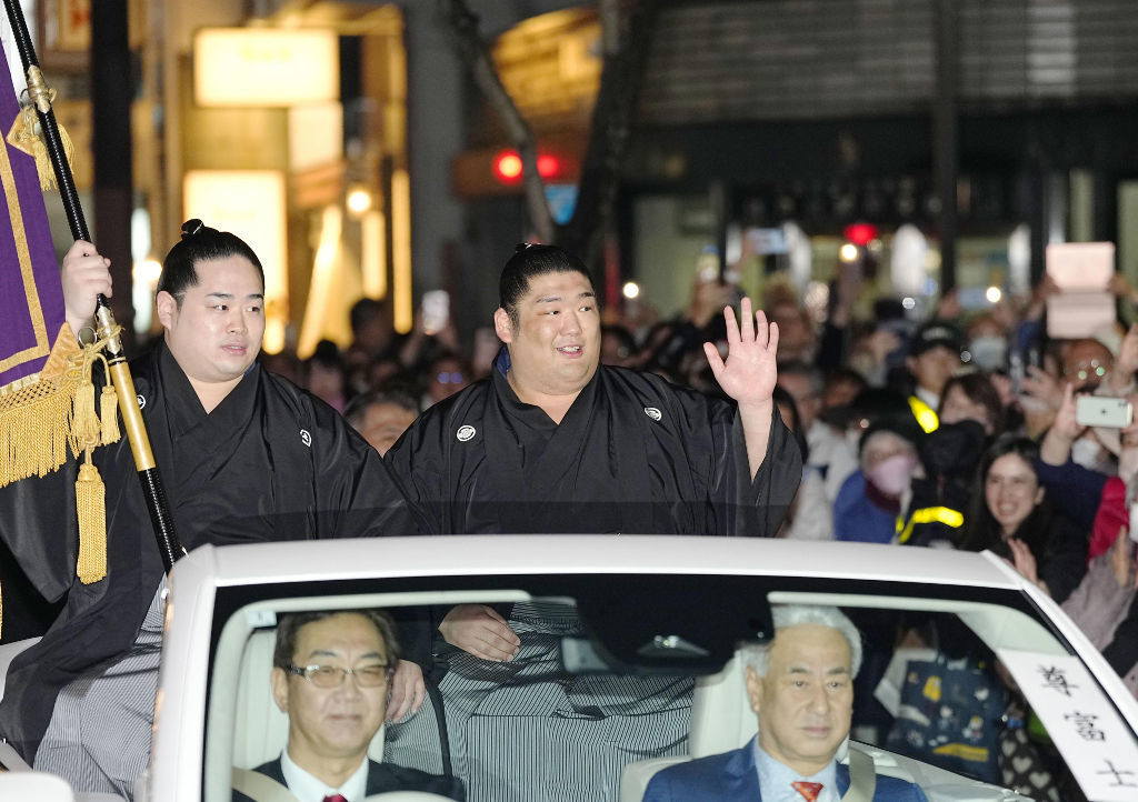 大相撲春場所で新入幕優勝を果たし、パレードに集まったファンに手を振る尊富士。左は錦富士＝２４日、大阪市