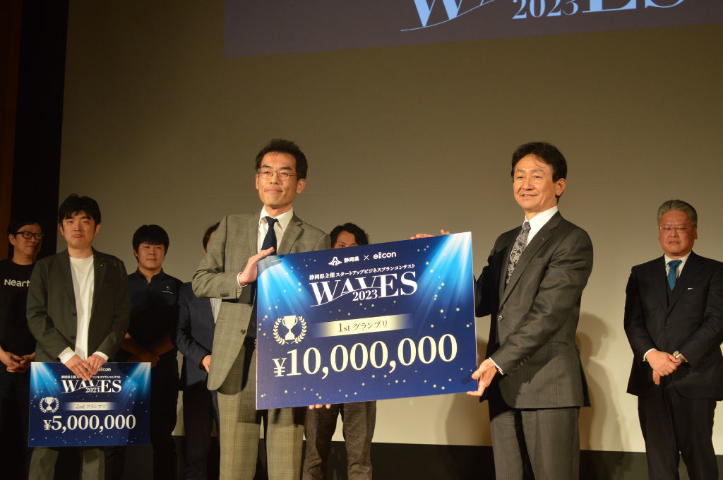 グランプリに選ばれ、賞金ボードを手にする代表の鈴木幹久さん（手前左）＝２６日午後、静岡市内