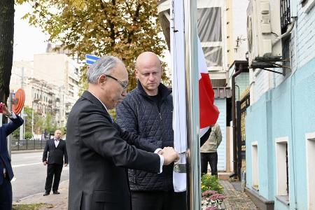 在ウクライナ日本大使館施設で日本国旗を掲揚する松田邦紀大使（左）＝２０２２年１０月、キーウ（共同）