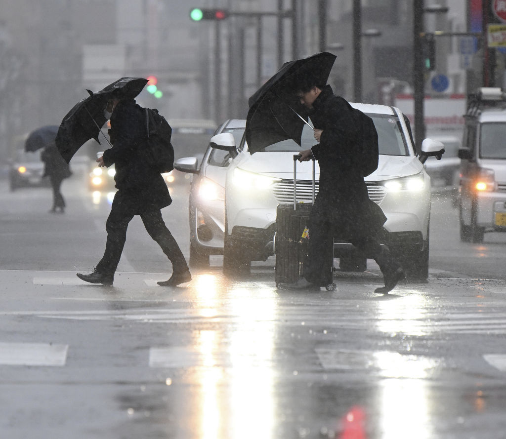 激しい風雨の中、傘を傾けて歩く人々＝２９日午前７時２０分、静岡市駿河区
