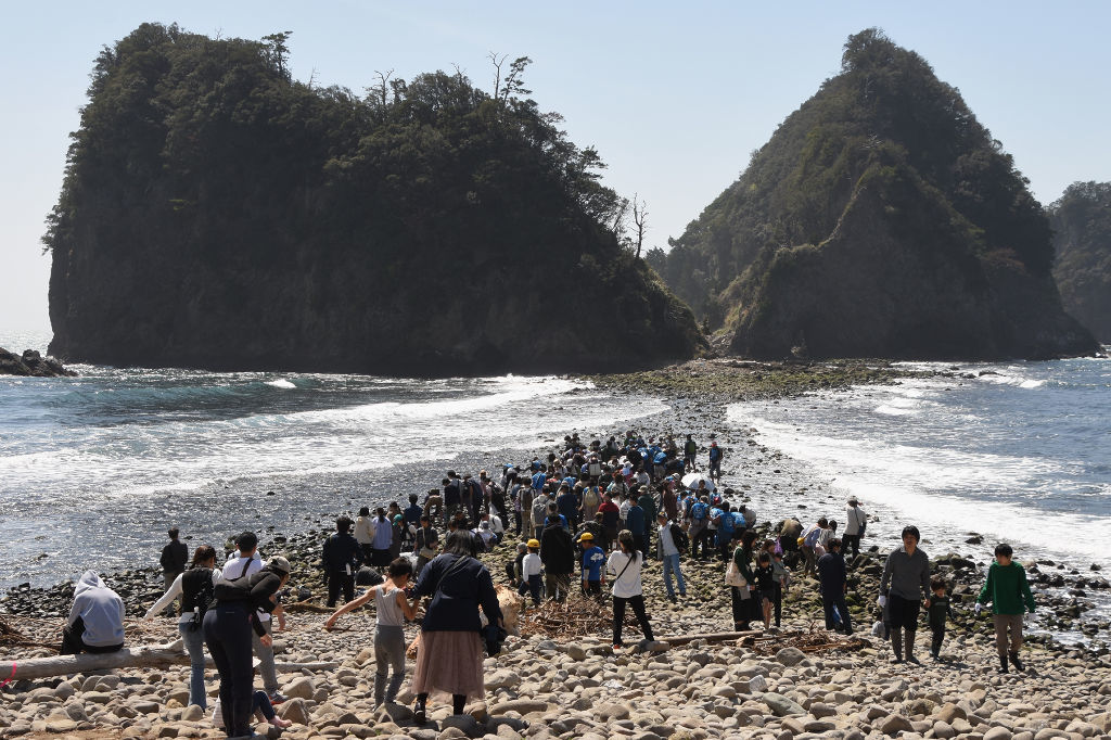 トンボロ現象によって出現した〝海の道〟を渡る観光客ら＝西伊豆町仁科の瀬浜海岸