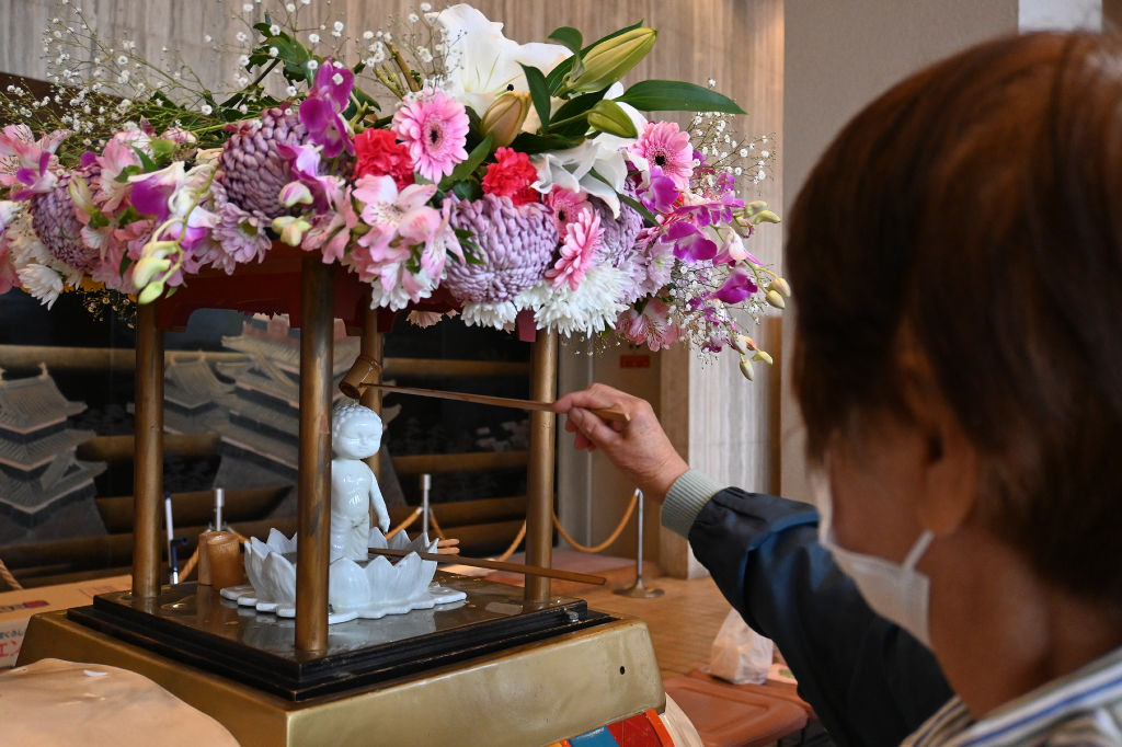 釈迦像に甘茶をかける参列者＝静岡市葵区の市民文化会館