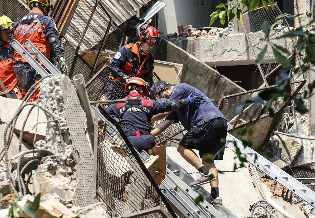 台湾北部・新北市で倒壊した建物から救助された人（右端）＝３日（中央通信社＝共同）