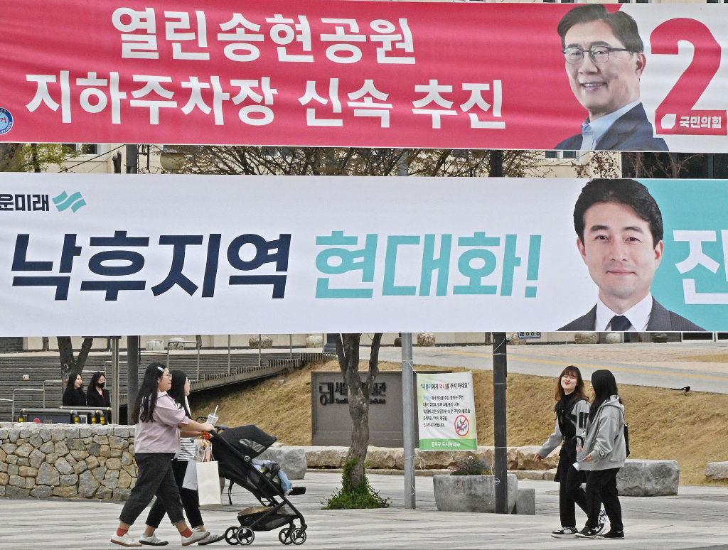 韓国総選挙候補者の横断幕の前を歩く子ども連れの女性ら＝３日、ソウル（共同）