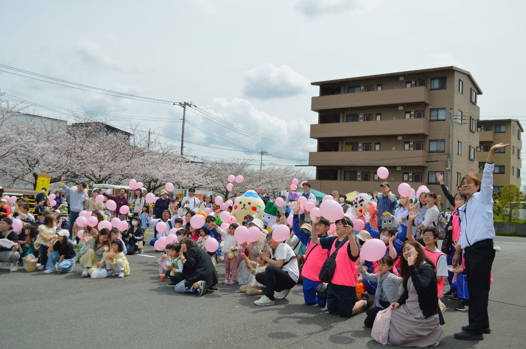 ピンクのバルーンを手に持ち、記念撮影をする来場者や実行委員ら＝長泉町桜堤
