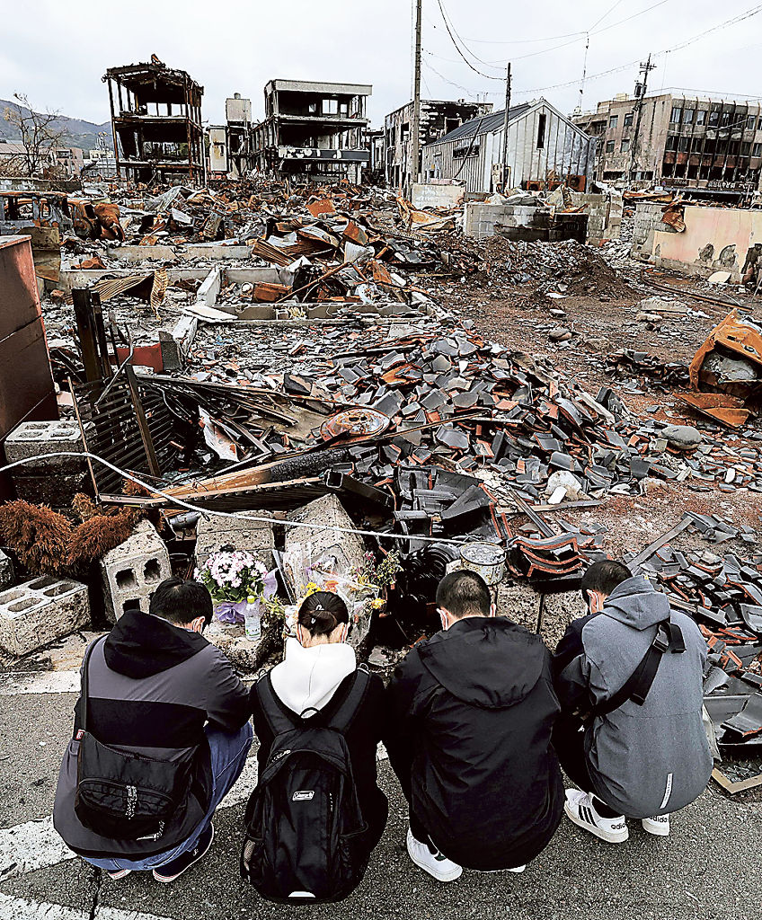 静かに手を合わせ　　地震による大規模火災で親族が犠牲となった「輪島朝市」周辺を訪れた家族。月命日に４人そろって来ることができないからと、この日を選んだ。「怖かったかな。この事実が、冗談であってほしいとどれほど思ったことか」と静かに手を合わせた＝３月２９日、石川県輪島市