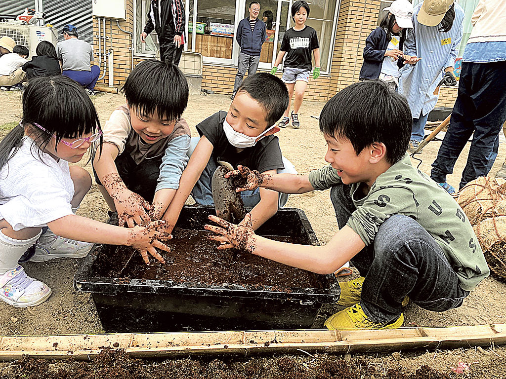 馬ふんと水を混ぜる作業をする児童＝浜松市中央区の富塚協働センター