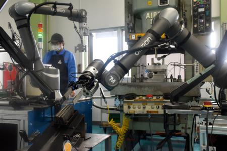 有川製作所の工場で導入されているオムロンのロボット（手前）＝３月、石川県津幡町
