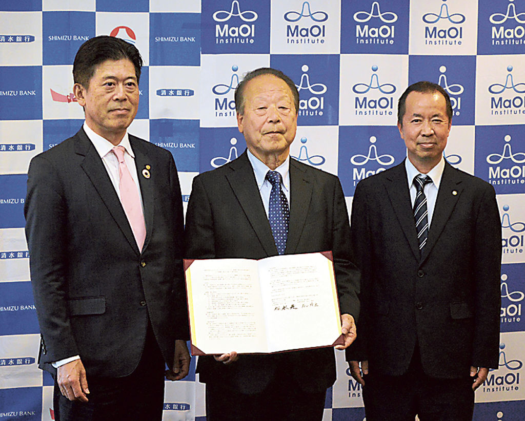協定を機に一層の関係強化を誓った岩山靖宏頭取（左）と松永是代表理事（中央）＝１８日午後、静岡県庁