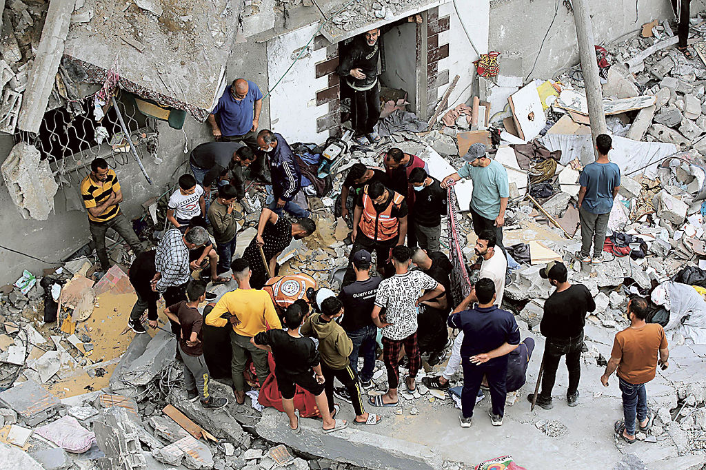 ２７日、ガザ地区中部デールバラハへのイスラエル軍の攻撃後、破壊された建物付近で救助に当たる人々（ゲッティ＝共同）