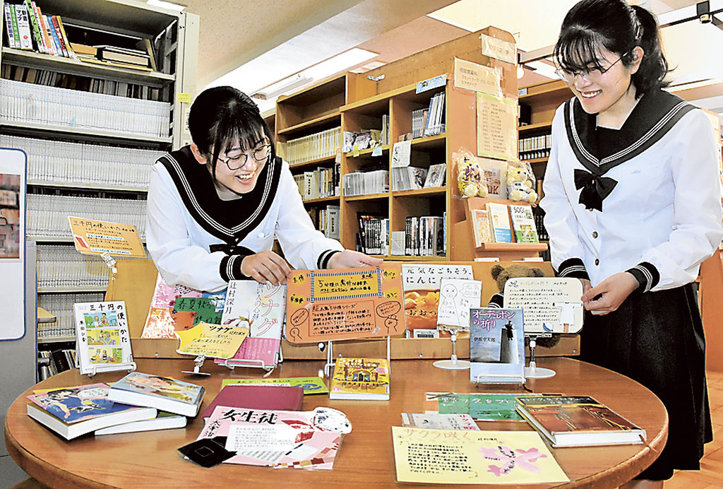 学校図書館のポップを飾る北村さん（左）と松並さん＝三島市の三島北高