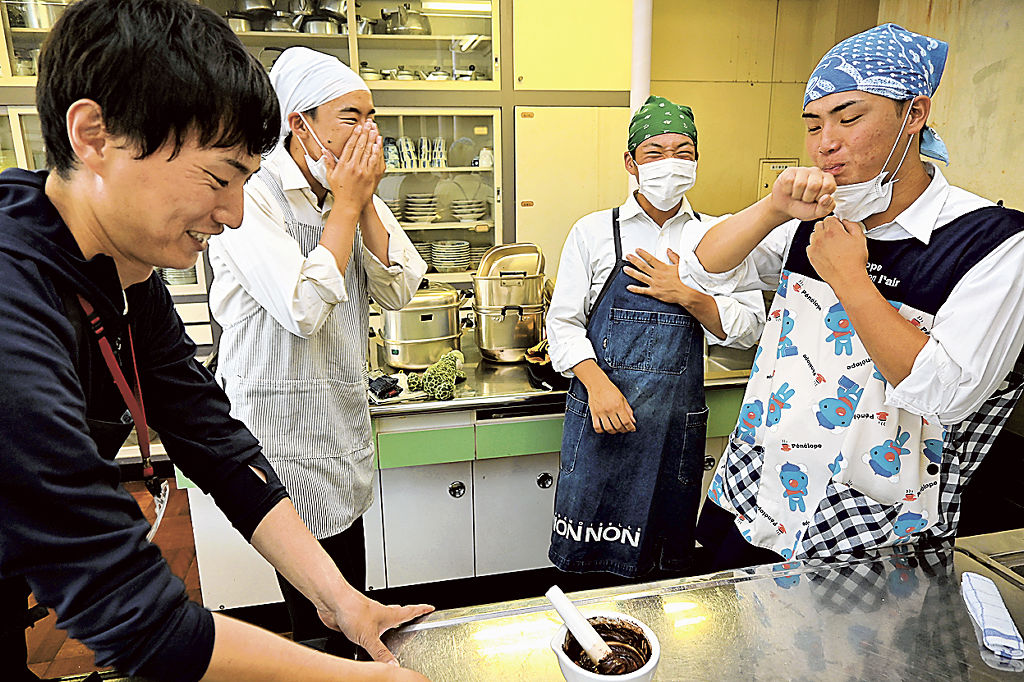 田中さん(左)の指導の下、砂糖やミルクを加えていない状態のチョコレートを味見する生徒=島田市の島田商業高