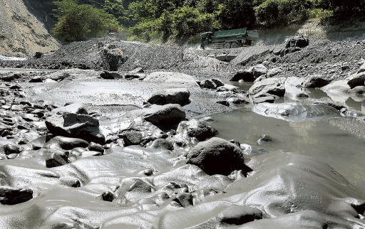 ニッケイ工業による凝集剤入り汚泥の不法投棄現場の下流。表面が固まり光沢のある”謎の泥”が一面を覆う＝８月下旬、山梨県早川町