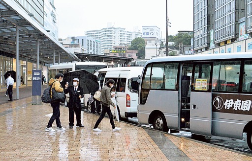 宿泊施設の送迎バスに乗り込む観光客。通常の金曜に比べ、駅周辺の人通りは少ない＝９日午後、ＪＲ熱海駅