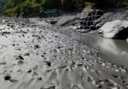 少なくとも８年近く続いた凝集剤入り汚泥の不法投棄現場の下流では、今も粘着質の泥が河床を覆っている＝８月下旬、山梨県早川町の雨畑川