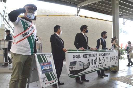 ホームで横断幕を掲げ、乗客を迎える関係者＝１２日午後、下田市の伊豆急下田駅