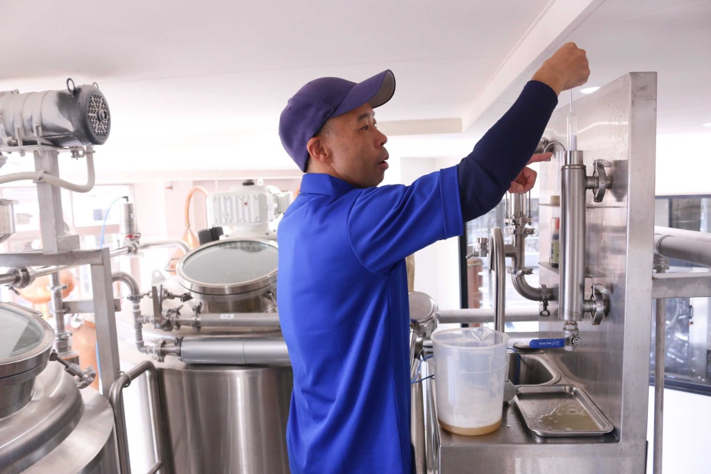 麦汁を発酵させた「若ビール」の糖度を測定する冨川宏一さん＝１１日、富士市の時之栖富士