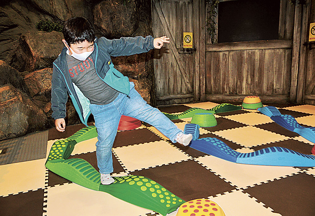 特殊な平均台でバランス感覚を試す子ども=富士市の道の駅「富士川楽座」
