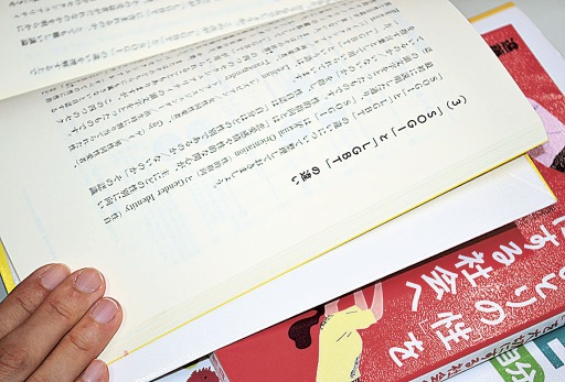 性に関する本を手に、「ＳＯＧＩ」について説明するケイさん＝７月下旬、静岡県内