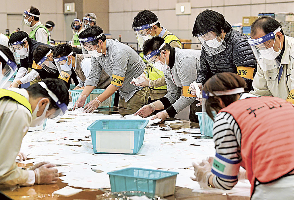 新型コロナウイルス感染対策のマスクとフェースガードをして開票作業を行う静岡市職員＝２８日午後、同市駿河区のツインメッセ静岡