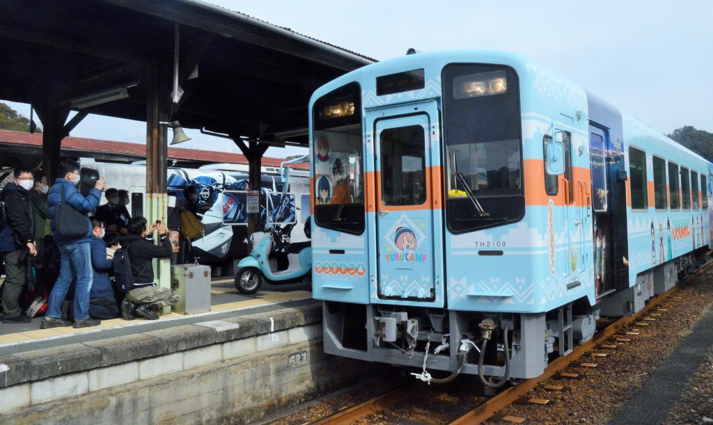 詰めかけたファンに初運行を見送られる「ゆるキャン△」のラッピング列車＝１２日午後、浜松市天竜区二俣町の天竜二俣駅