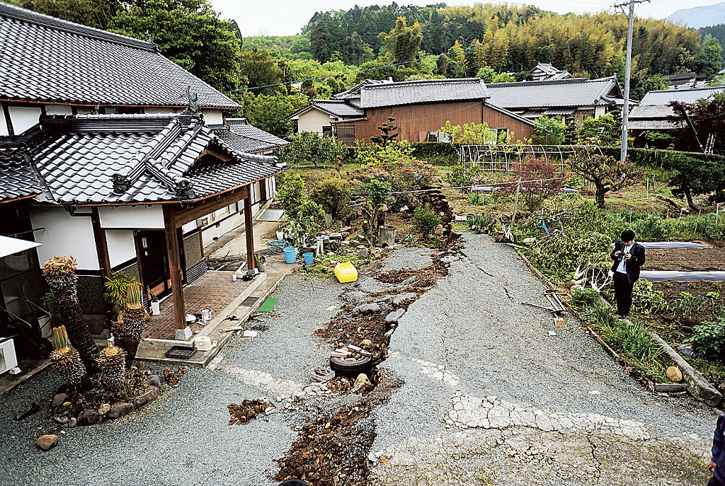 「本震」で民家の敷地に現れた布田川断層の一部。現在はシートで覆われ、母屋（左）は基礎だけが残る＝２０１６年４月、熊本県益城町（同町提供）