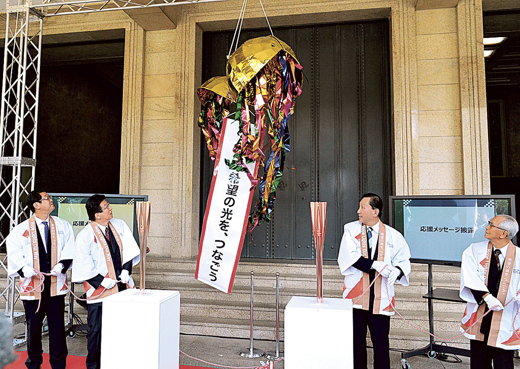 聖火リレーのトーチ到着を祝い、くす玉割りを行う関係者＝３月２４日午前、静岡県庁前