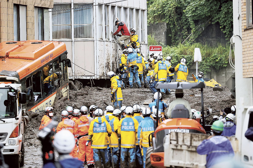 土石流が発生した現場で、警察官らに救助される男性(奥)=4日午後、熱海市伊豆山