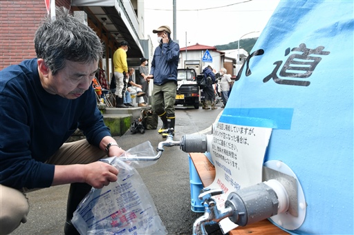 給水所で水を受け取る住民＝５日午前８時４０分ごろ、熱海市の仲道公民館
