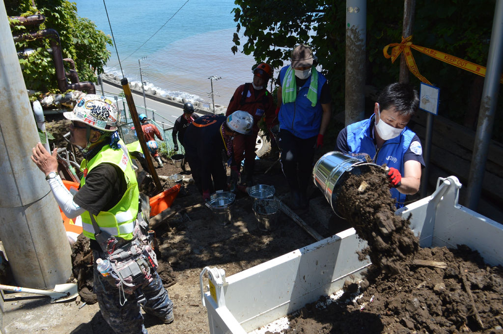 道にたまった土砂の撤去作業に汗を流すボランティア＝２１日午前、熱海市