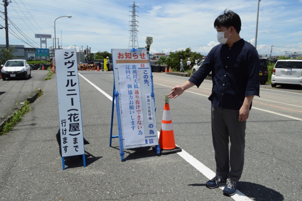 店舗まで通行可能なことを示す看板を見つめる三保貴広さん＝７月１６日、清水町長沢
