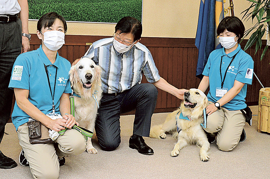 川勝平太静岡県知事（中央）を訪問したファシリティドッグのヨギ（左）と後任のタイ（右）＝１日午後、県庁