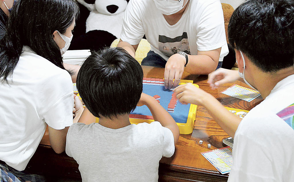 「てのひら」の居場所で、ボードゲームを楽しむ子どもと学生ボランティア＝静岡市駿河区